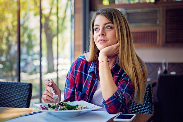istock Young woman is eating salad in a restaurant 1295075155