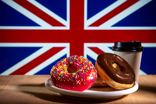 Fresh donuts in plate, British flag in background.