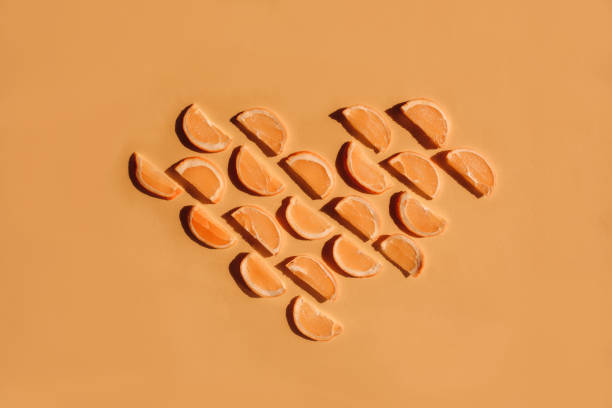 istock Orange slices arranged in seamless pattern on yellow and orange background. Heart shape made with orange and citrus slices. 1295076070