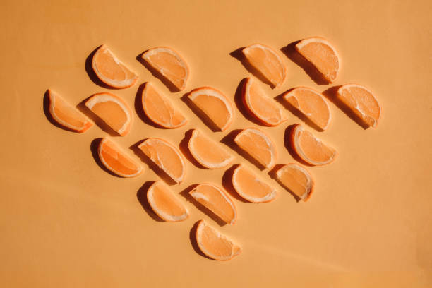 istock Orange slices arranged in seamless pattern on yellow and orange background. Heart shape made with orange and citrus slices. 1295076083