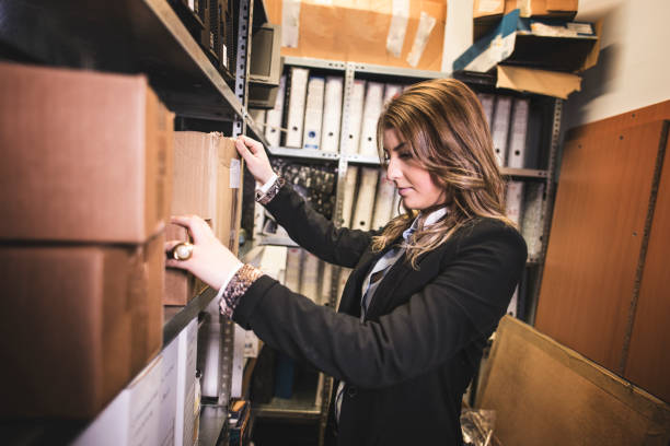 Attractive woman searches archive basement for old documentation and files stock photo