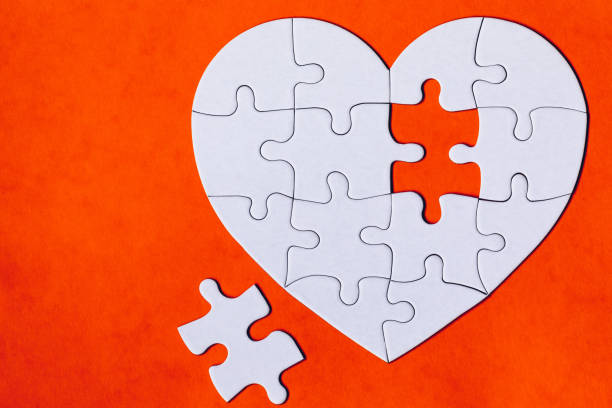 istock Heart-shaped jigsaw puzzle on color background. Puzzle heart on wooden background. A missing piece of the heart puzzle. Heart shape jigsaw puzzle. Puzzles in the shape of a heart. 1295078083
