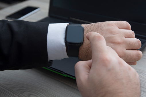 A businessman using smartwatch while working at the office stock photo