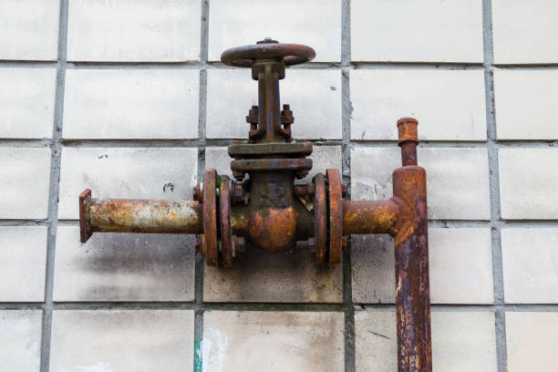 istock Old fire pipe system closeup fire hydrant detail. Rusty fire hydrant on the background of old tiles on the wall 1295081240
