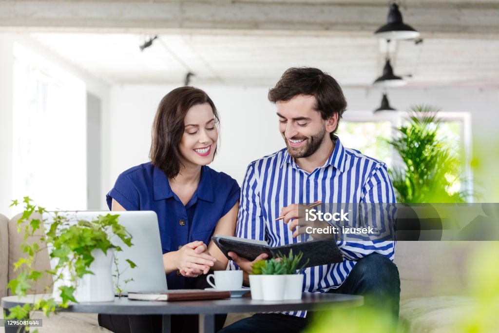 Coworkers working in the eco-friendly green office Mid adult women and man sitting on sofa in the creative workplace and working together, discussing agenda. 30-39 Years Stock Photo