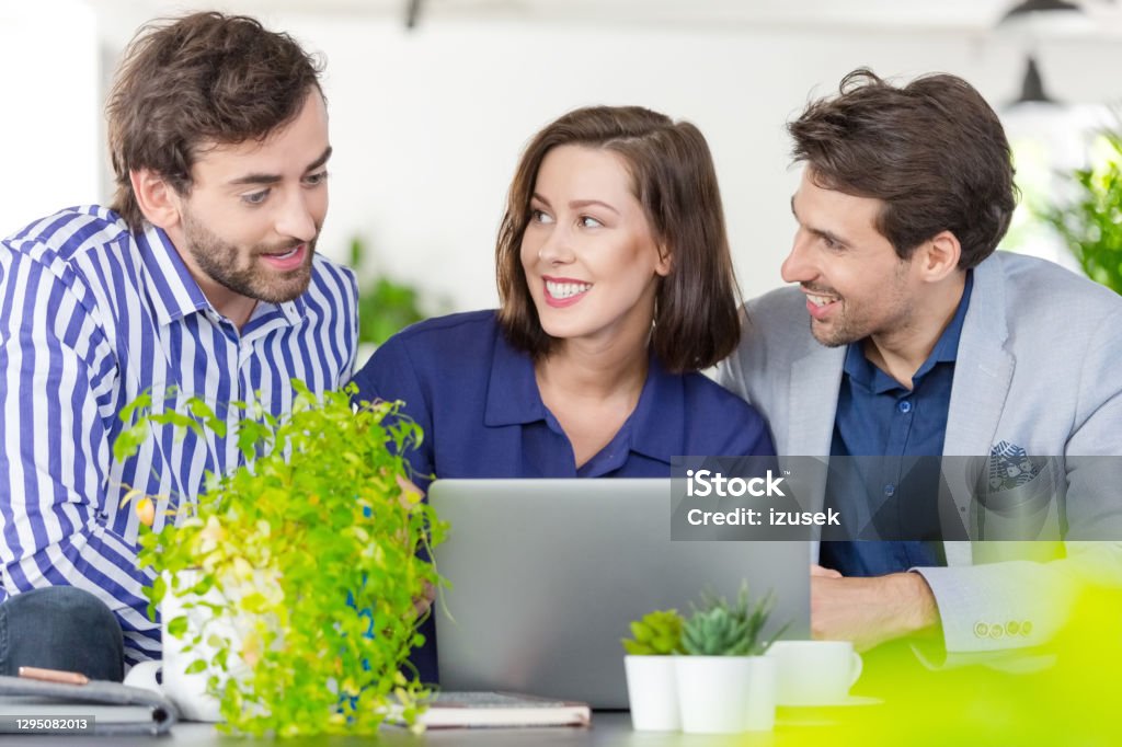 Creative team working in a green office Mid adult women and men sitting on sofa in the creative eco-friendly workplace, working together over laptop. 30-39 Years Stock Photo Creative team working in a green office Mid adult women and men sitting on sofa in the creative eco-friendly workplace, working together over laptop. 30-39 Years Stock Photo