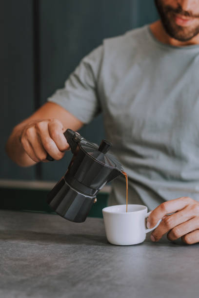 istock Unrecognizable Man Pouring Coffee from a Moka Pot in his Office 1295082926