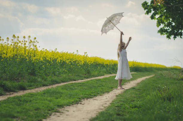 白い日よけ傘でポーズをとっている美しいブロンドの女の子 - footpath single lane road road farm ストックフォトと画像