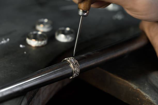 close-up of hand of a goldsmith setting the diamond on the ring. craft jewelery making with professional tools - cast in stone imagens e fotografias de stock