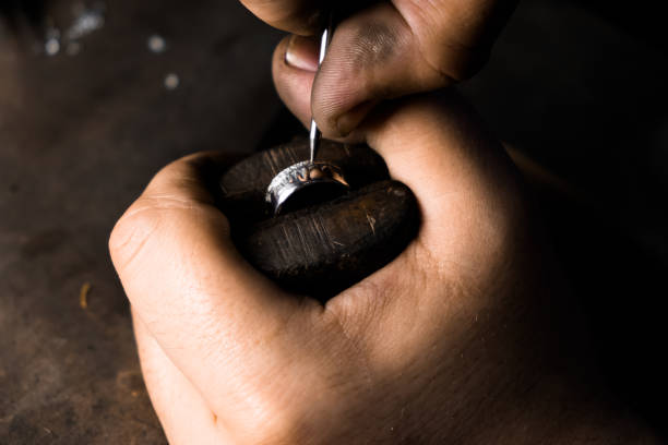 close-up of hand of a goldsmith setting the diamond on the ring. craft jewelery making with professional tools - cast in stone imagens e fotografias de stock