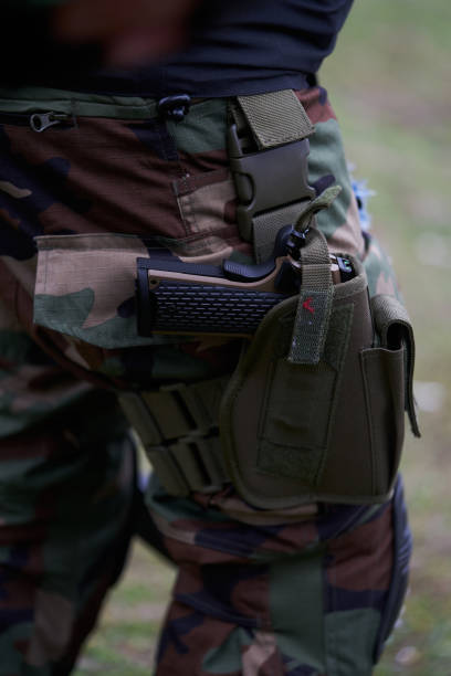 close-up de uma pistola em um coldre na perna de um soldado de uniforme - conciliator - fotografias e filmes do acervo