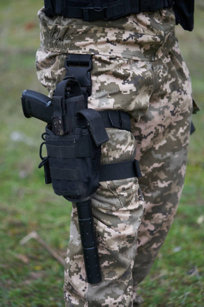 close-up de uma pistola com um silenciador em um coldre na perna de um soldado de uniforme - conciliator - fotografias e filmes do acervo