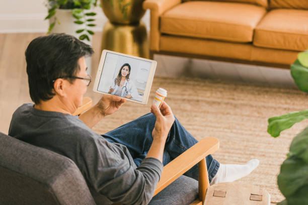 Man talks with doctor during telemedicine appointment During a virtual appointment, a senior man discusses his current medications with a female doctor. telemedicine stock pictures, royalty-free photos & images