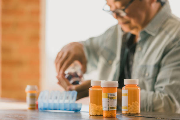 istock Senior man places medication in pill organizer 1295099817