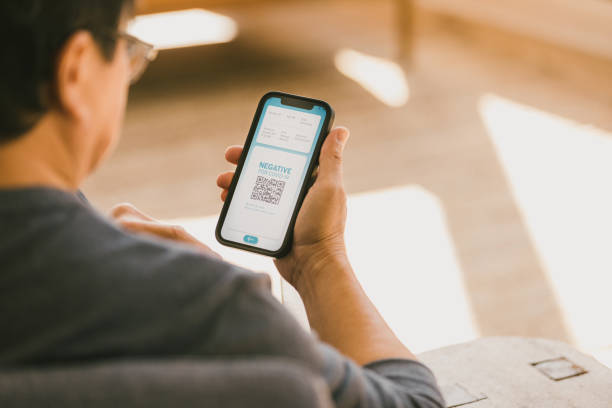 Man receives negative COVID test result A relieved senior man receives a negative COVID-19 test result. He is looking at the test result on his smartphone. man looking at phone over shoulder stock pictures, royalty-free photos & images