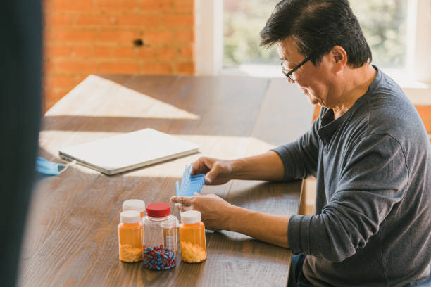 istock Man sorts medication into pill organizer 1295099845