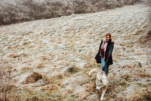 Young beautiful female enjoying walking her husky dog in a forest