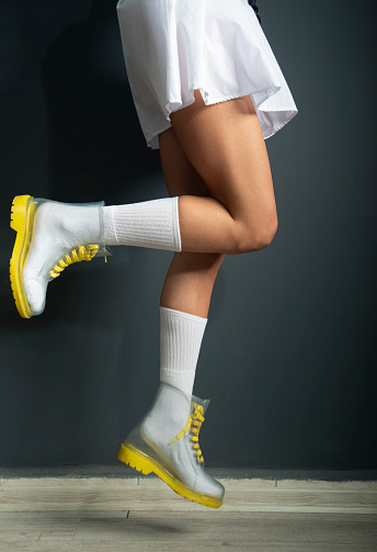 White short socks, transparent yellow boots, leg detail photo. Two legs jumping. dark background