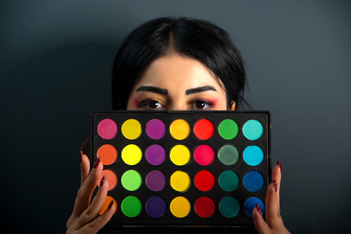 Colorful makeup palette in young woman's hands. Tinted eyeshadows. Cosmetics. Eye detail.