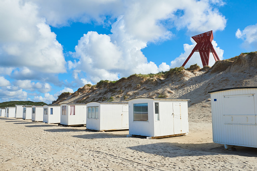 Classic white beach huts at Loekken beach at the west coast of Jutland, close to the red beacon on the sand dunes.