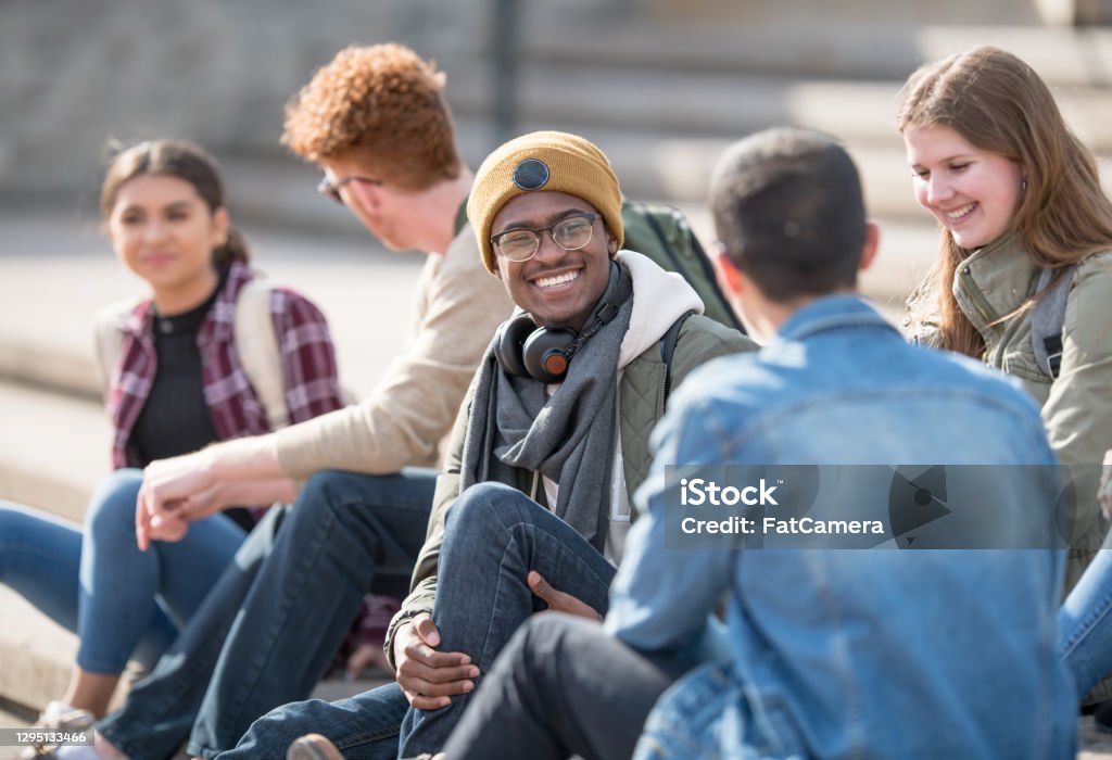 Hanging out on campus A multi ethnic group of university students are hanging out outdoors on campus. University Student Stock Photo