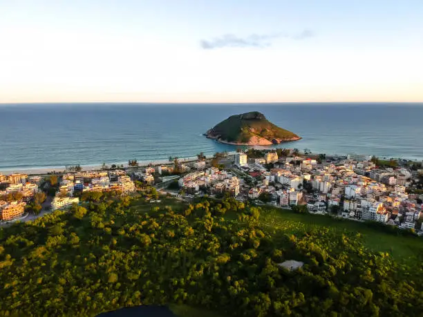 Photo of aerial landscape photo of Recreio dos Bandeirantes beach during sunset, with views of Chico Mendes park and the Pontal Stone bathed by orange sunlight