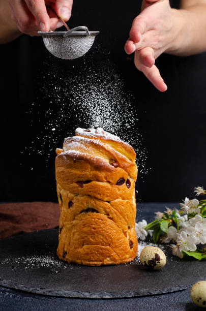 istock Female hands sprinkle with powdered sugar craffin cake on a black background. 1295141724
