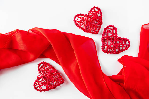 istock Red hearts and silk ribbon on a white background 1295151030