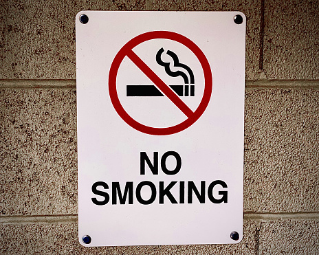 A red and white no smoking sign on a brick wall