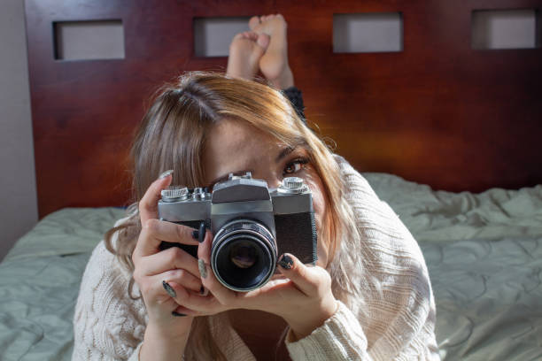 istock beautiful and sexy woman in bed using old camera 1295167189