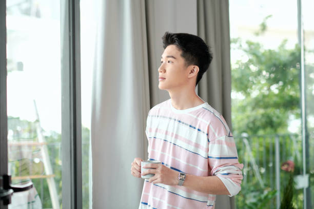 istock young handsome man drinking morning coffee by the window in his home 1295171530