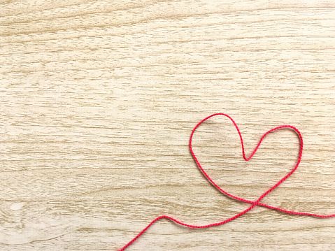 There is a heart made of red yarn in the lower right corner of the table.