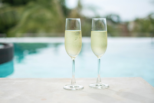 Two sparkling champagne glasses or prosecco near swimming pool. Summer travel, vacation, holiday and weekend concept
