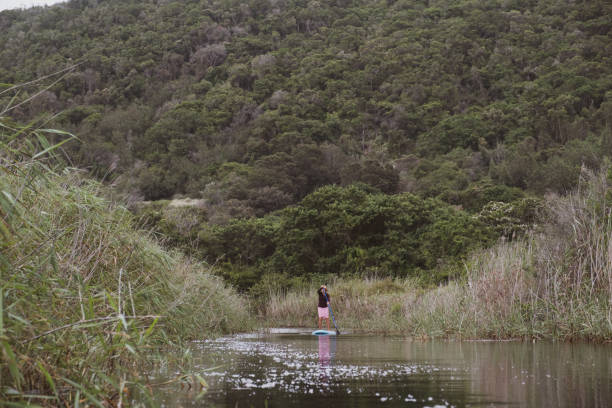 Woman stand up paddle boarding on a pristine river