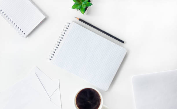 istock Female workspace with open notebook and pencil on a white table. Work from home, blogger workplace. 1295204602