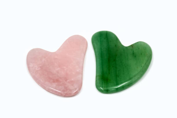 strumento di massaggio raschiatura del corpo gua sha verde e rosa. facial natural jade stone board guasha cure. - alternative therapy massaging clinic health spa foto e immagini stock