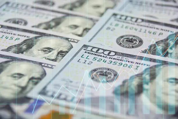 Photo of Financial data analysis graph over one hundred US dollar bills background