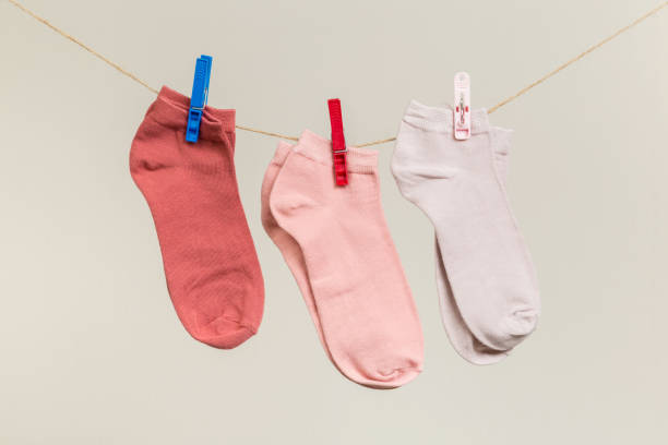 istock multicolored socks, dry after washing, hanging on a clothesline with clothespins on a light background 1295207749