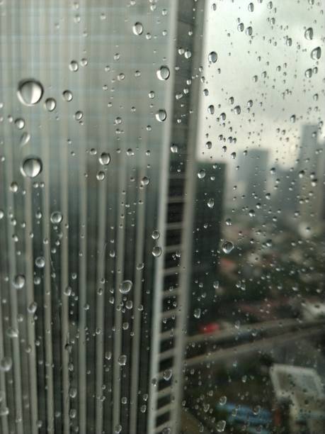 istock Water droplets - raindrop with blurry city and building background 1295212496