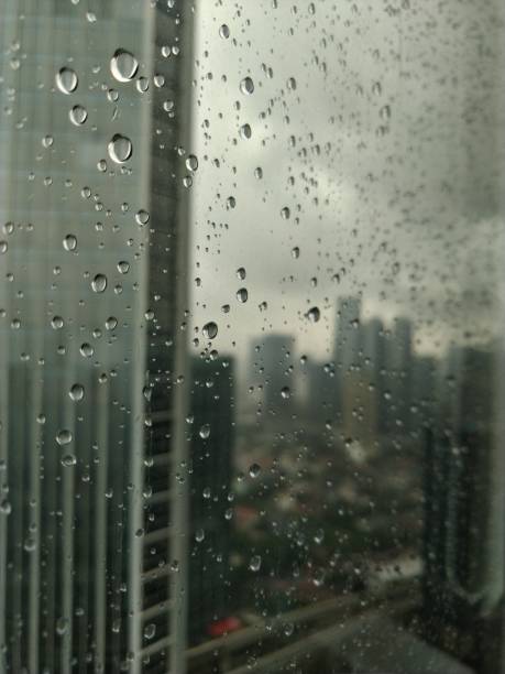 istock Water droplets from rain with blurry city building in background 1295212530