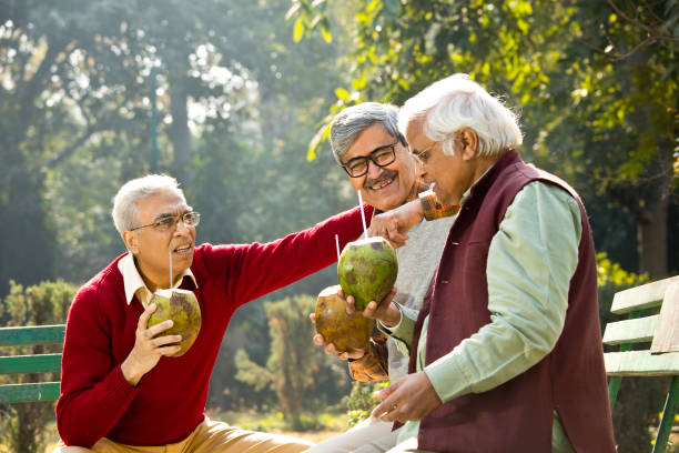 istock Senior men enjoying fresh coconut drink at park 1295213178