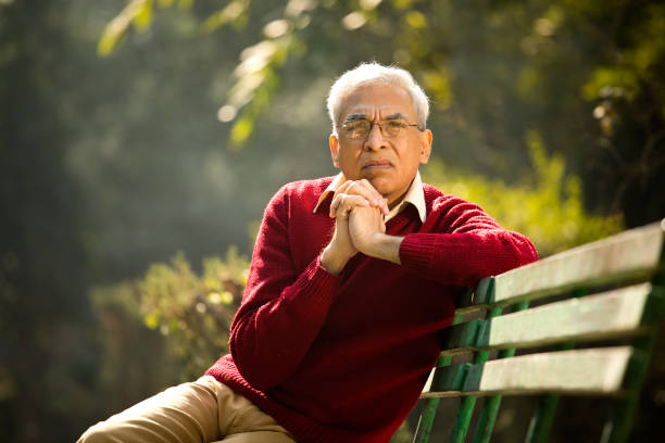 istock Senior man sitting at park bench 1295213826
