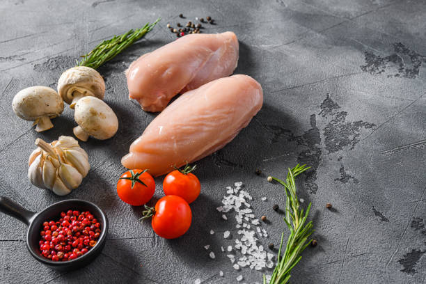 istock Raw organic chicken breast on a grey background. Food preparation, side view space for text. 1295215122