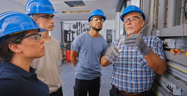 istock Electrician teaching his apprentices to connect the wires 1295215830