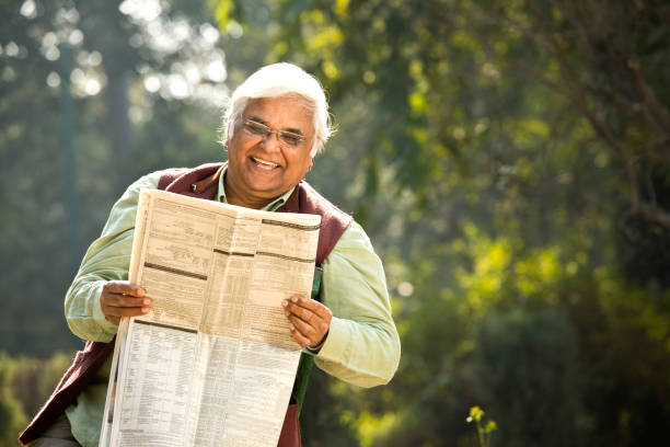 istock Senior man reading newspaper in the park 1295217640