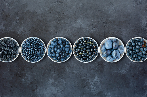 Berries in plates on a black concrete background. Copy space. Flat top view