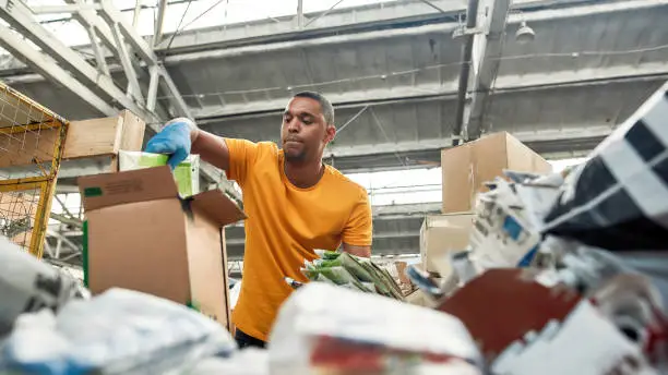 Photo of Young man packing boxes with waste paper