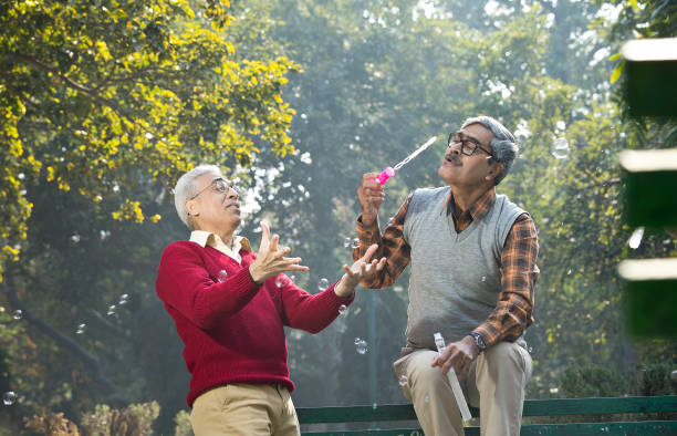 istock Two senior men enjoying blowing bubbles at park 1295225873