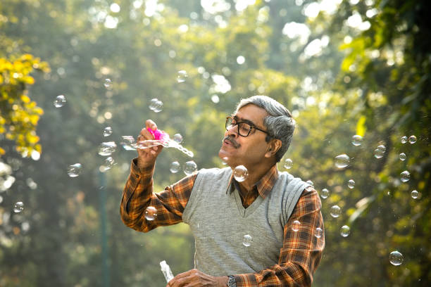 Senior men enjoying blowing bubbles at park