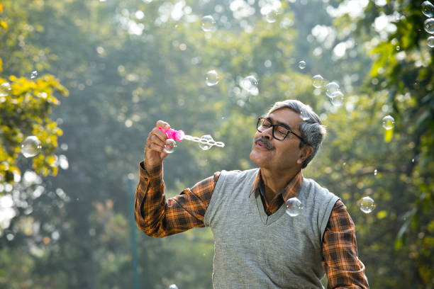 istock Senior men enjoying blowing bubbles at park 1295226004
